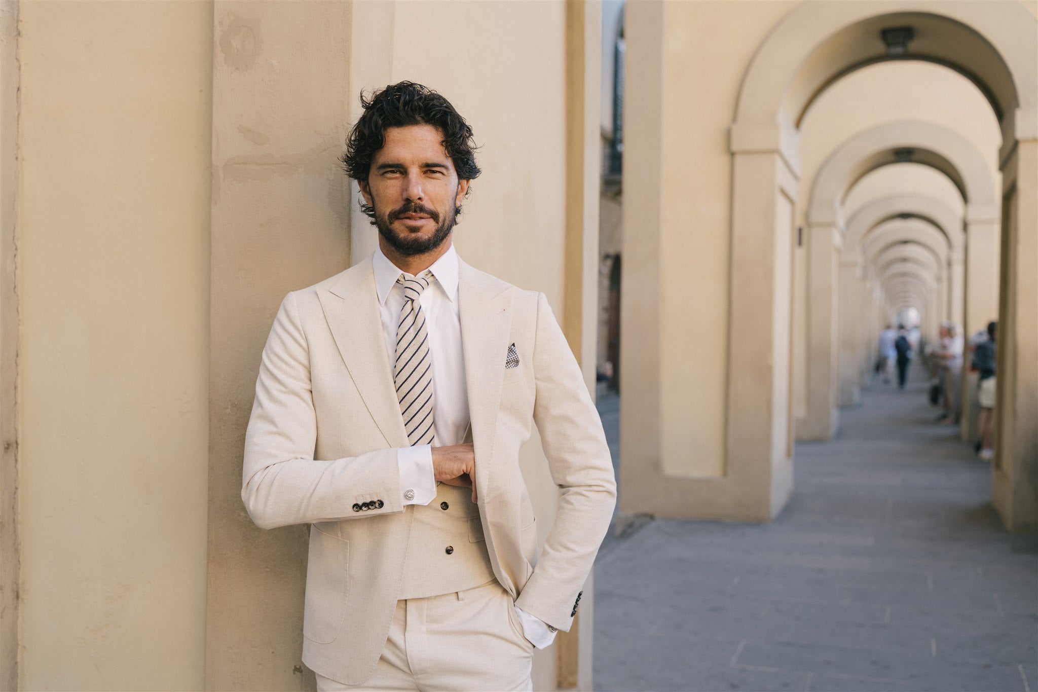 Man in a beige suit standing in an archway