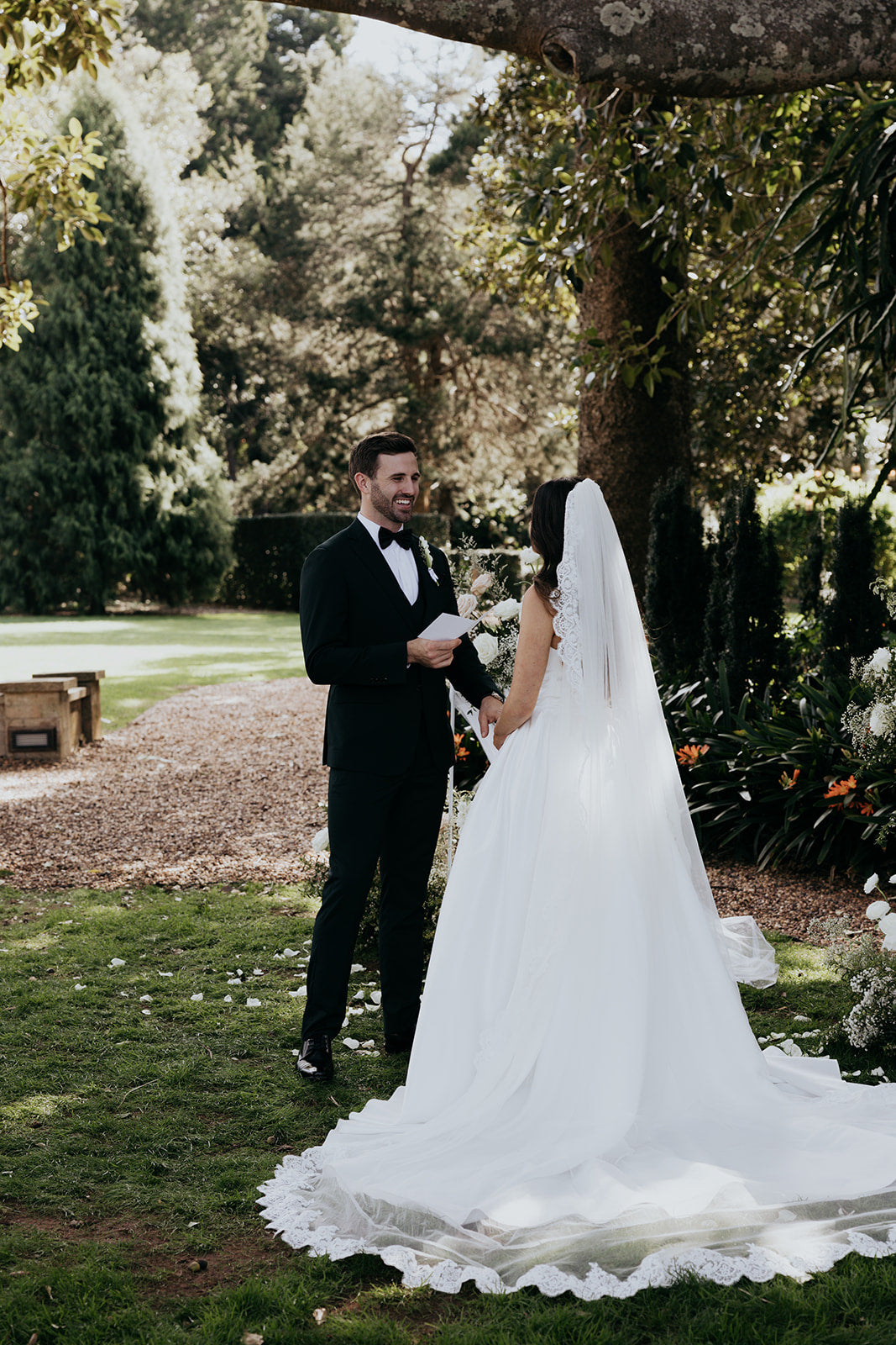 Wedding couple standing in a garden with trees and greenery.
