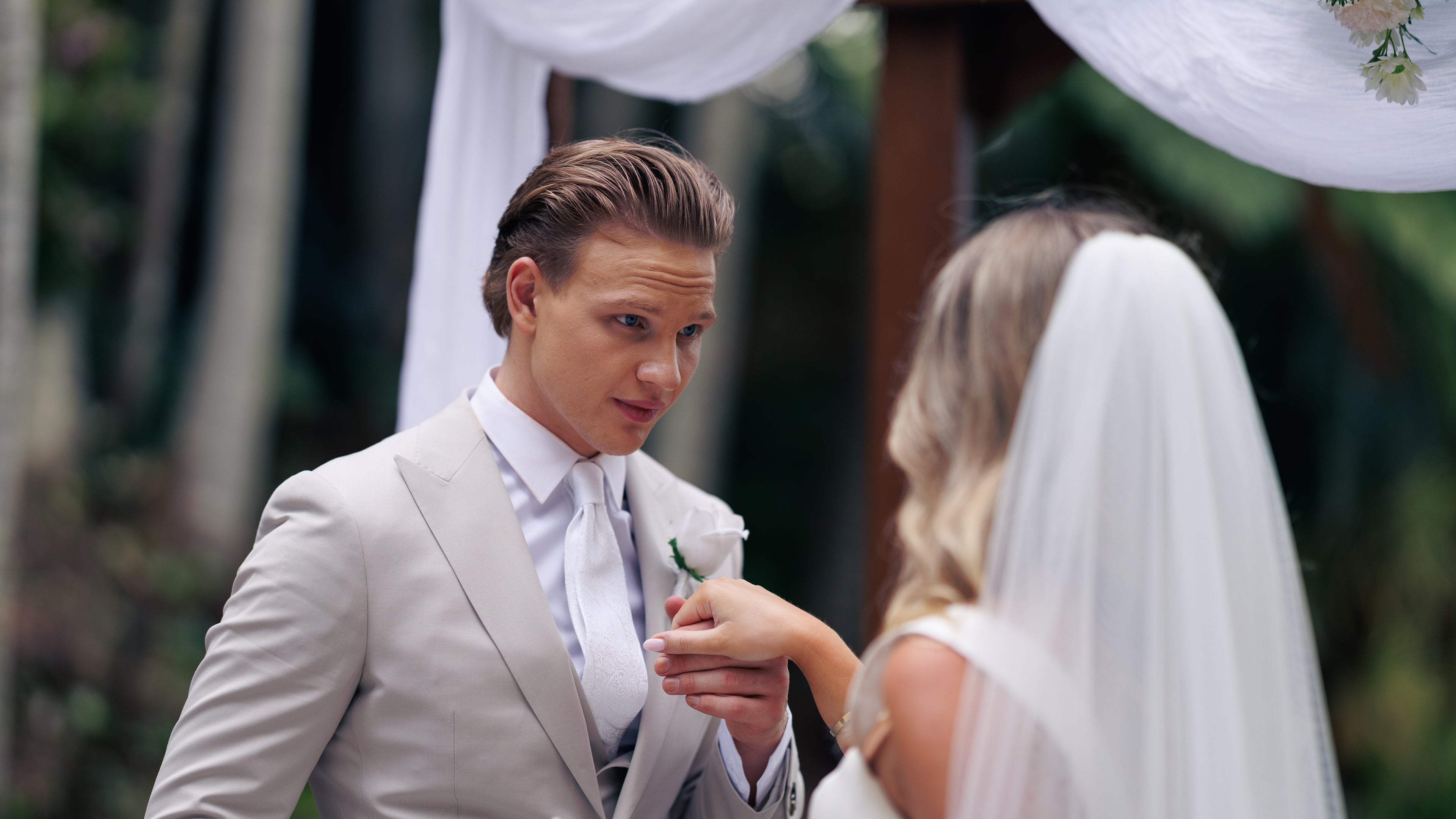 Man in a suit and woman in a wedding dress holding hands outdoors
