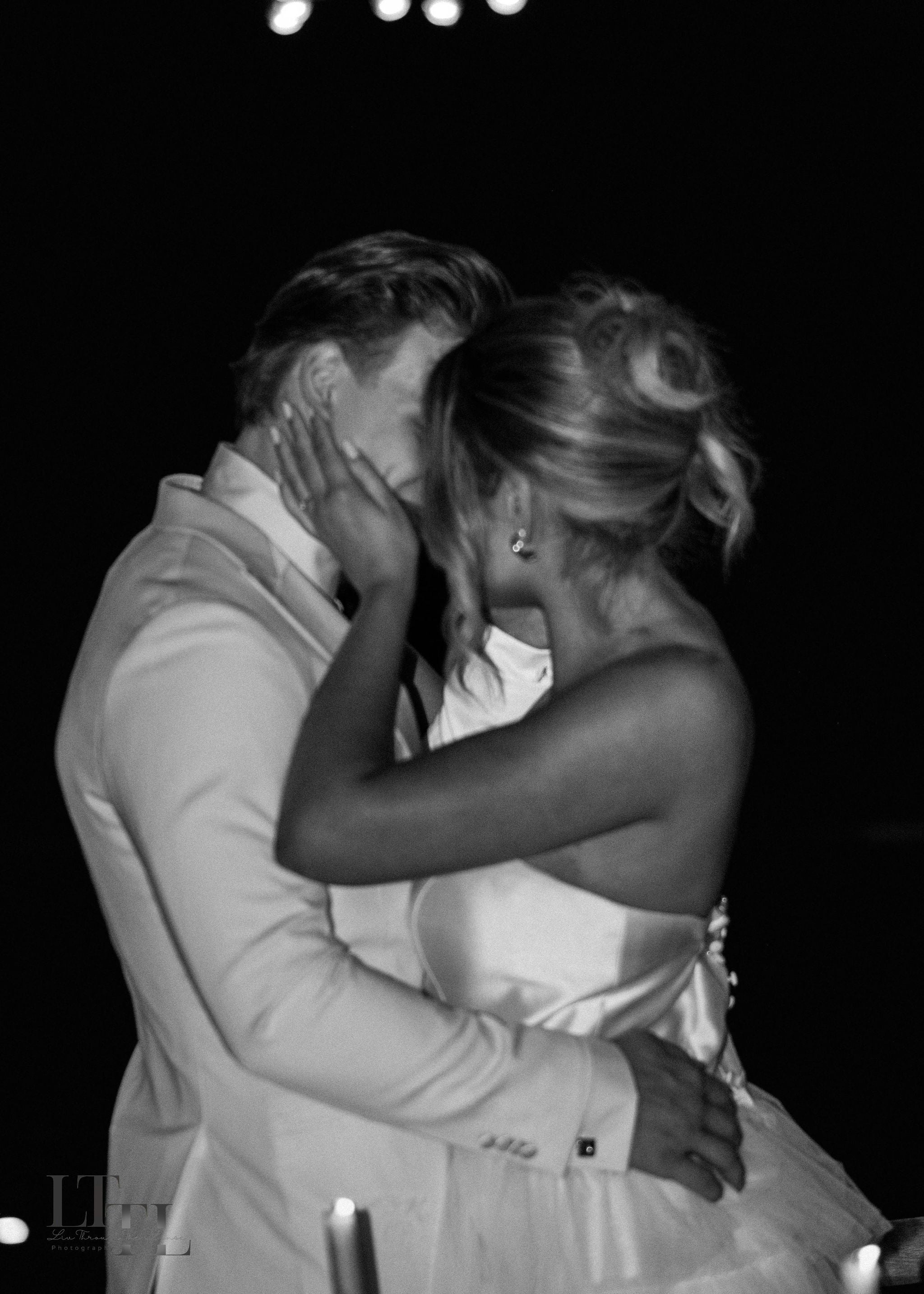Black and white photo of a couple embracing with a dark background