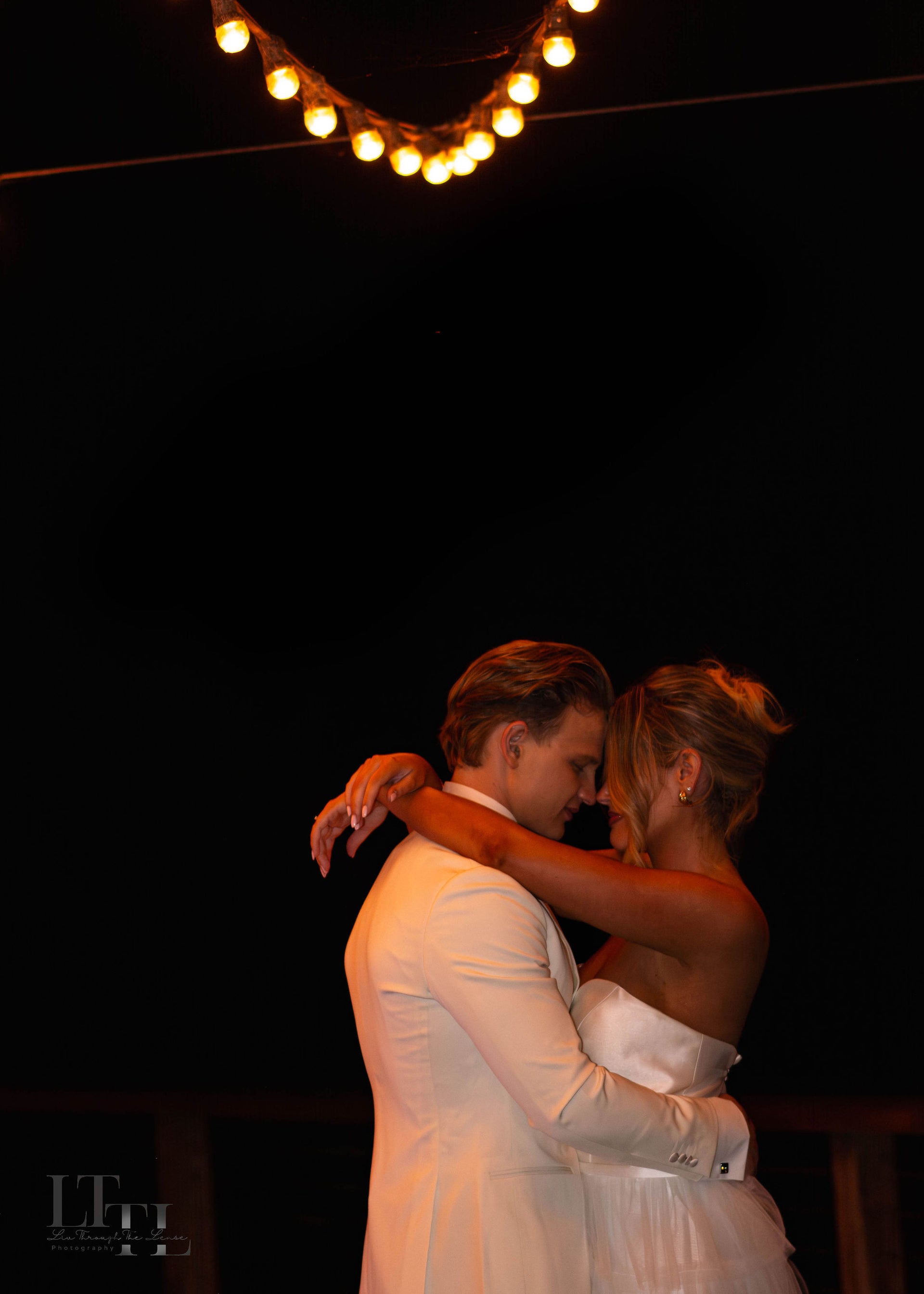 Couple embracing under string lights at night