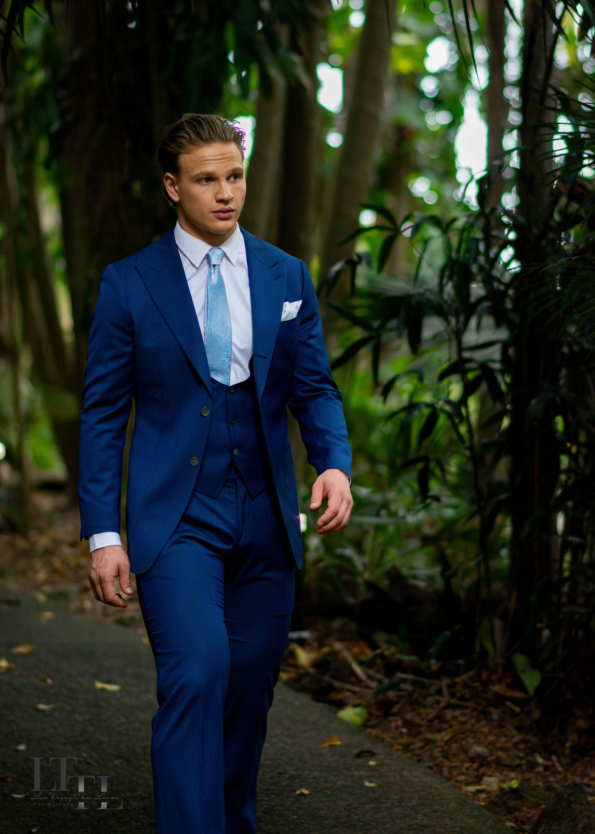 Man in a blue suit walking through a forest
