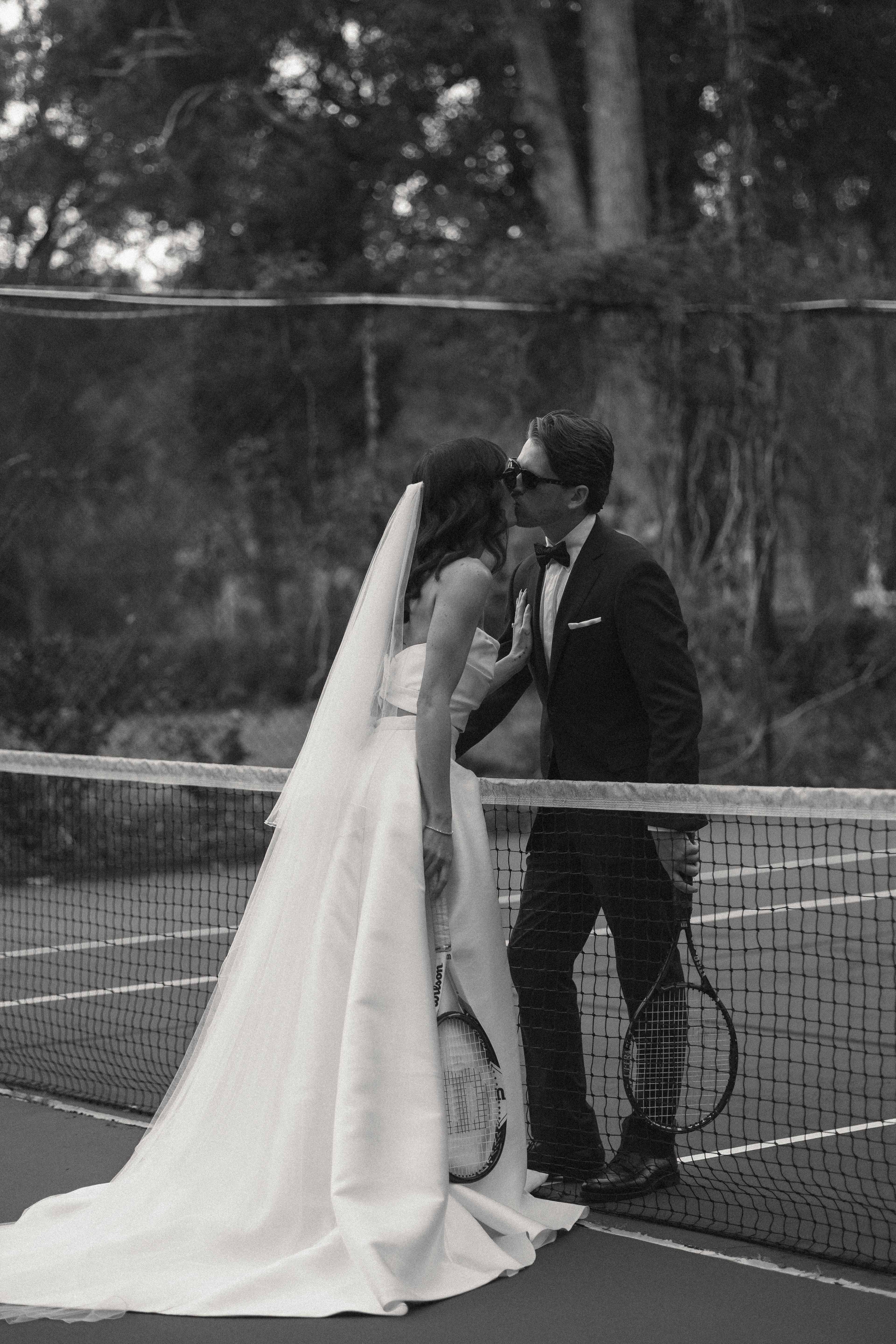 Black and white photo of a bride and groom on a tennis court.