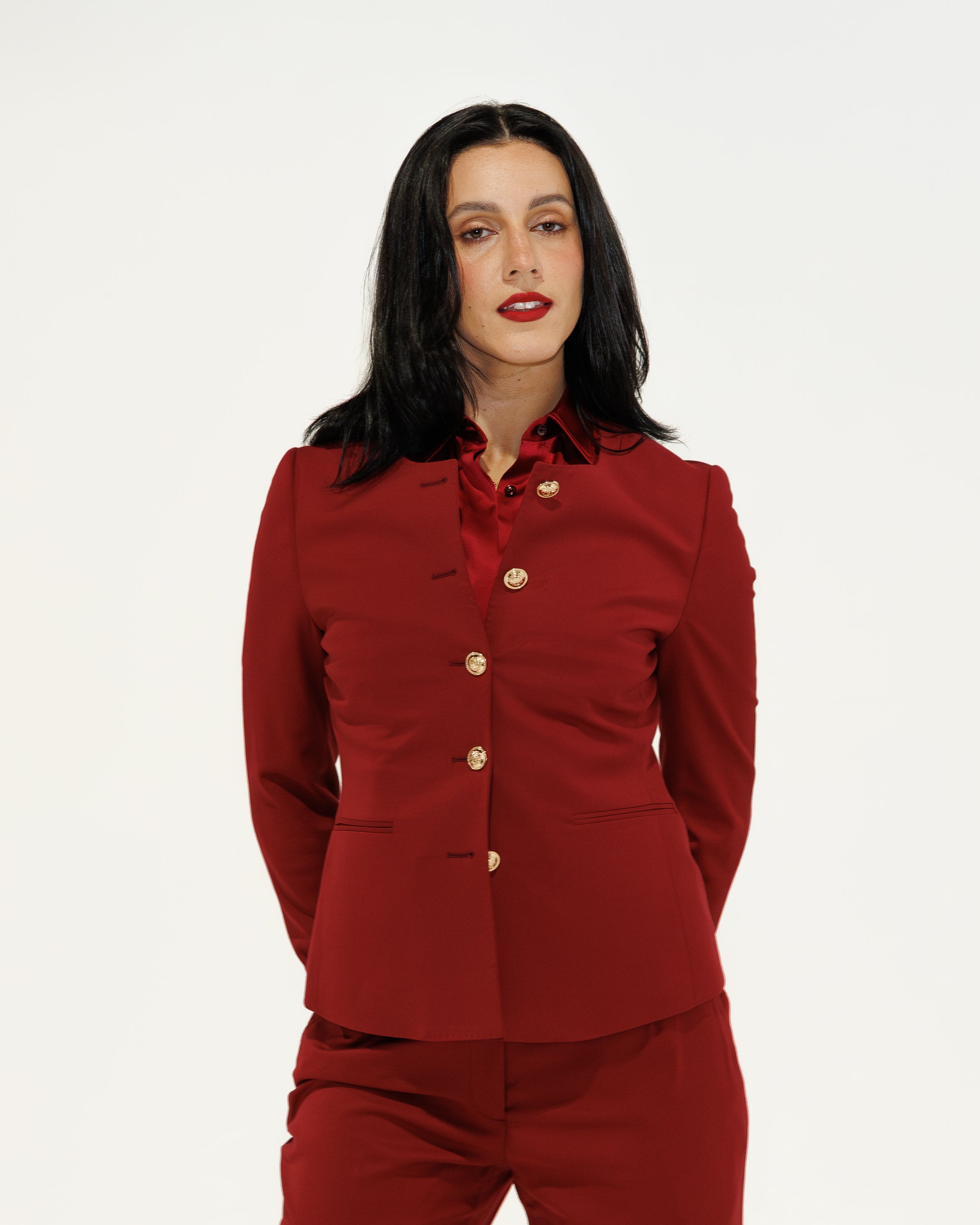 Woman wearing a red suit with gold buttons on a white background
