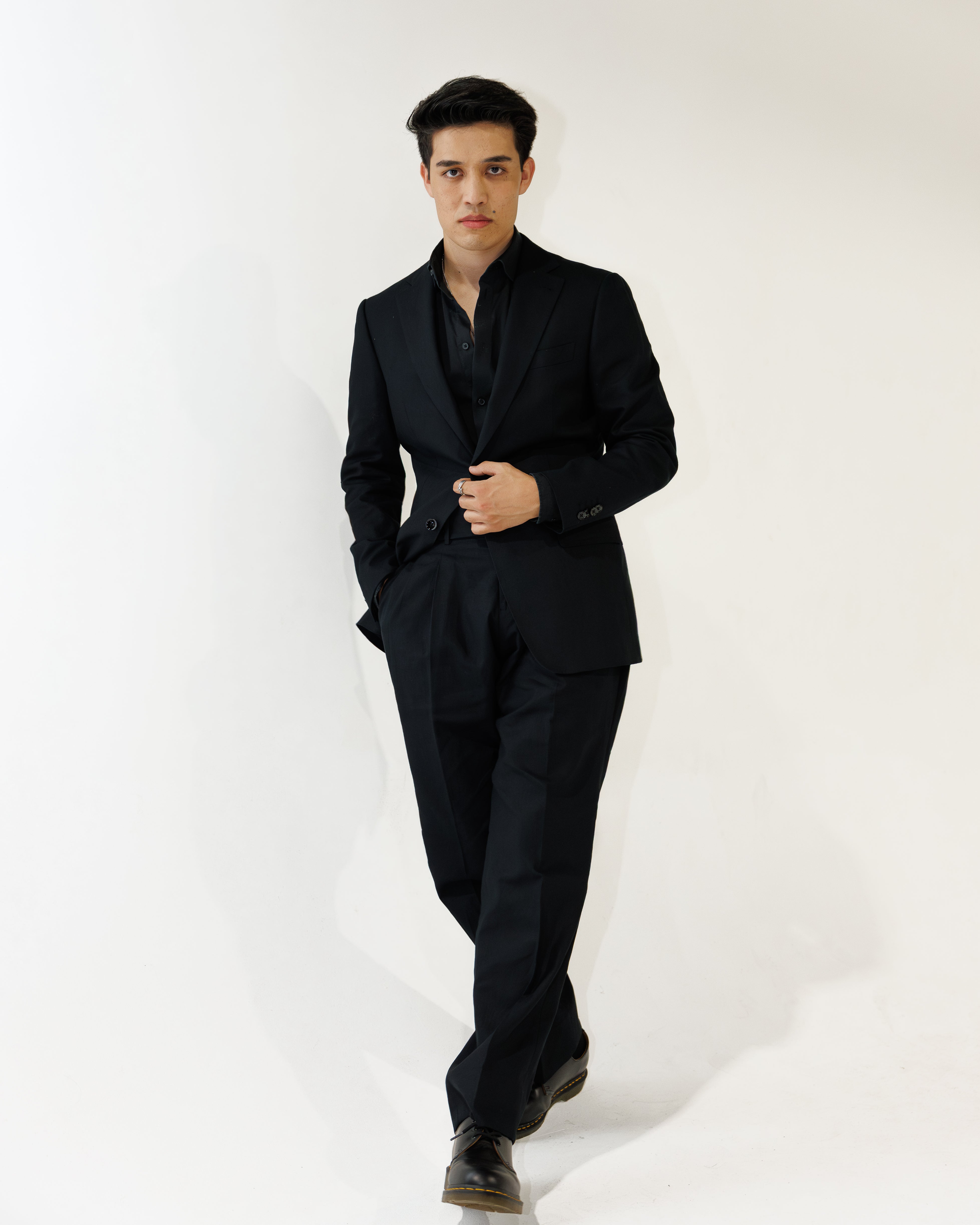 Man wearing a black linen suit against a white background