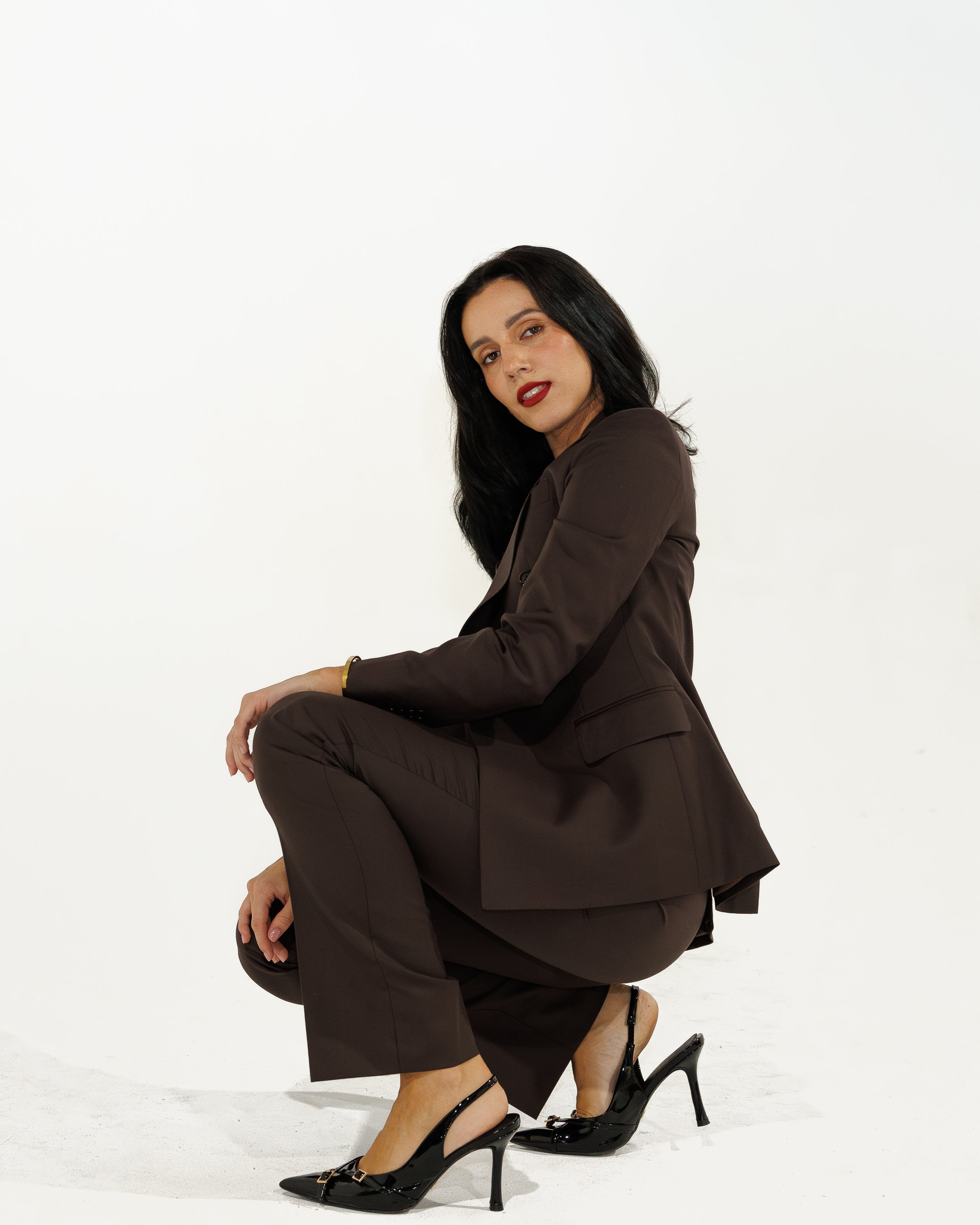 Woman in a brown suit sitting on a white background