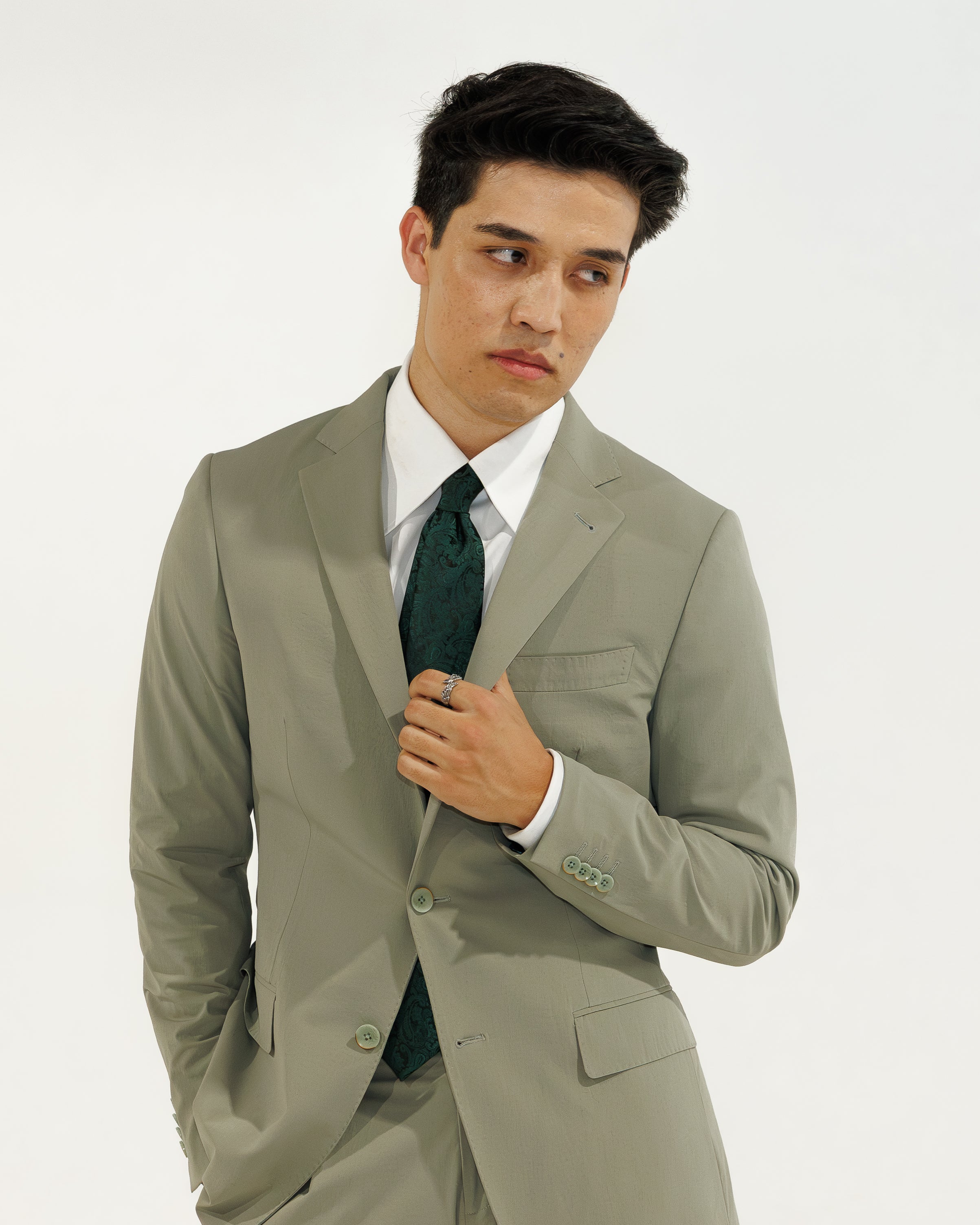 Man wearing a light green suit with a white shirt and dark green tie on a white background