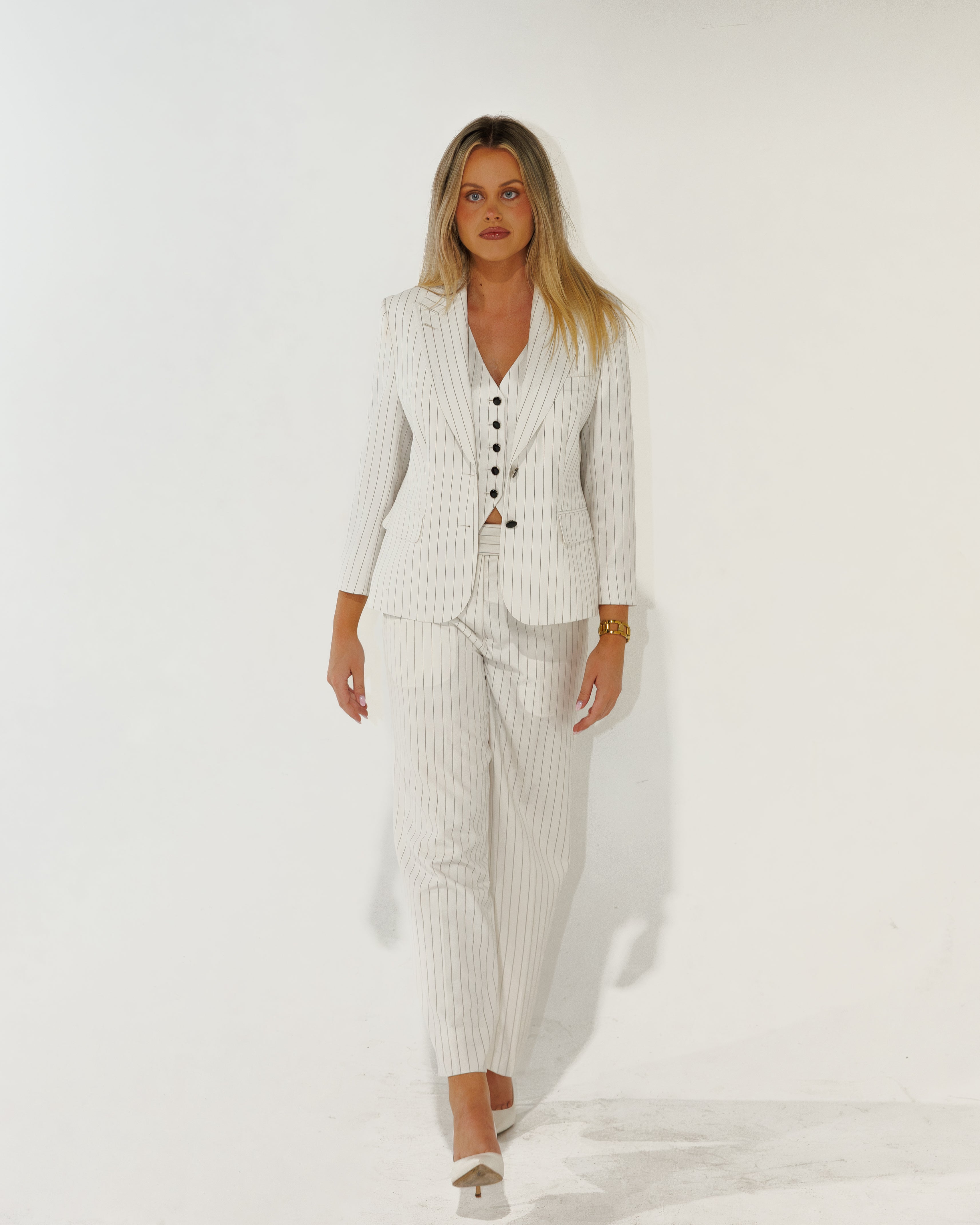 Woman wearing a white pinstripe suit against a white background