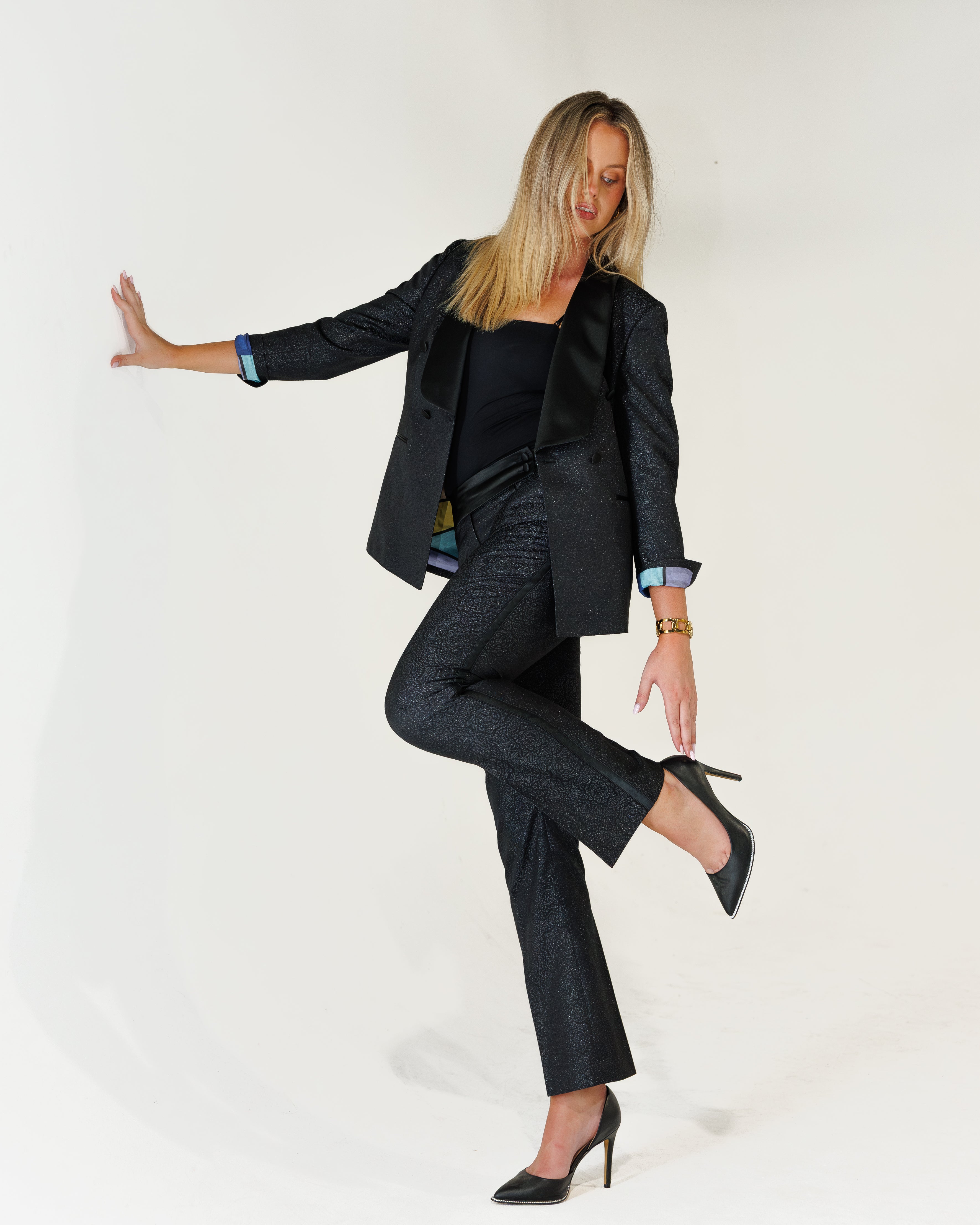 Woman in a navy sparkly tux posing against a white background