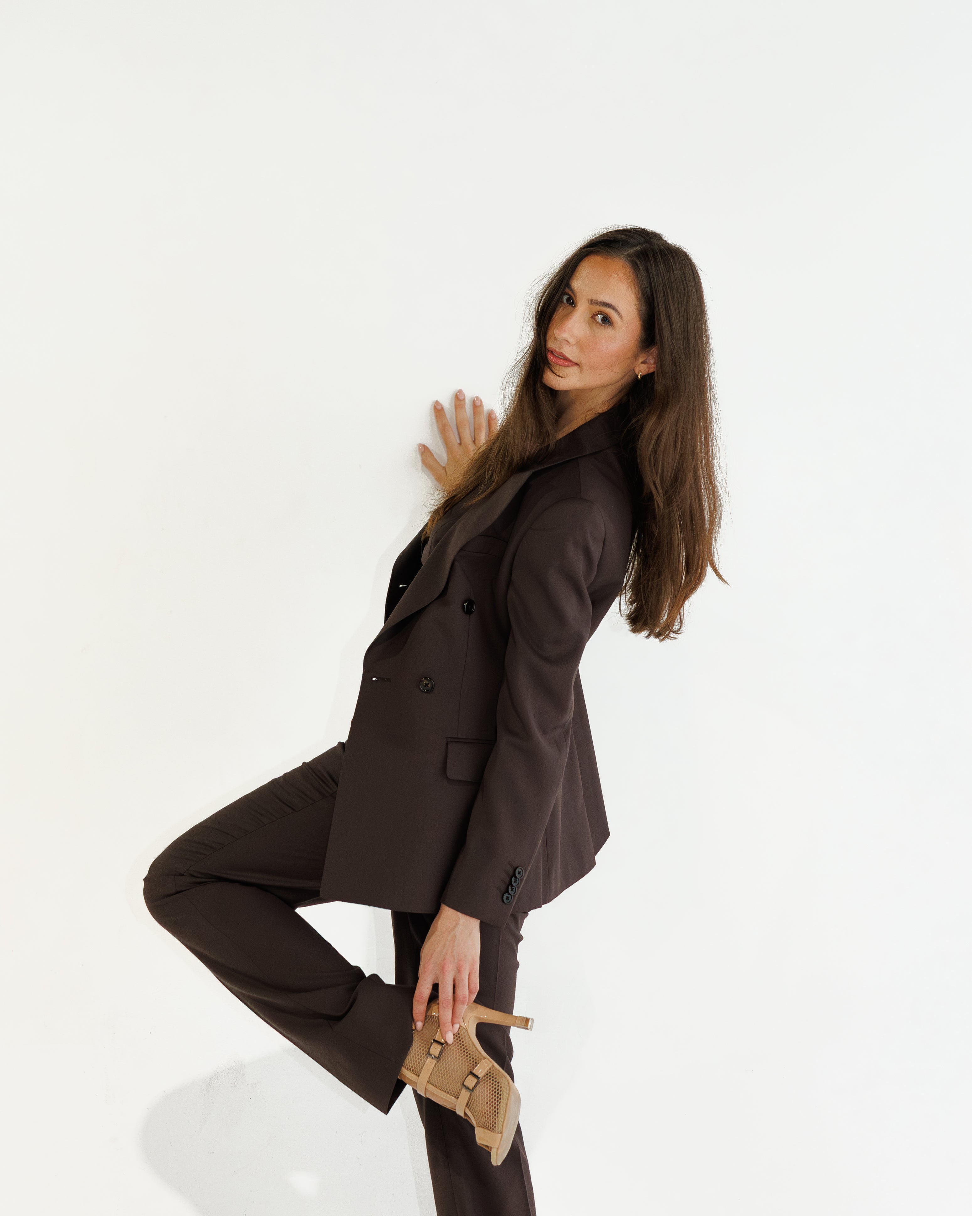 Woman in a brown suit posing against a white background