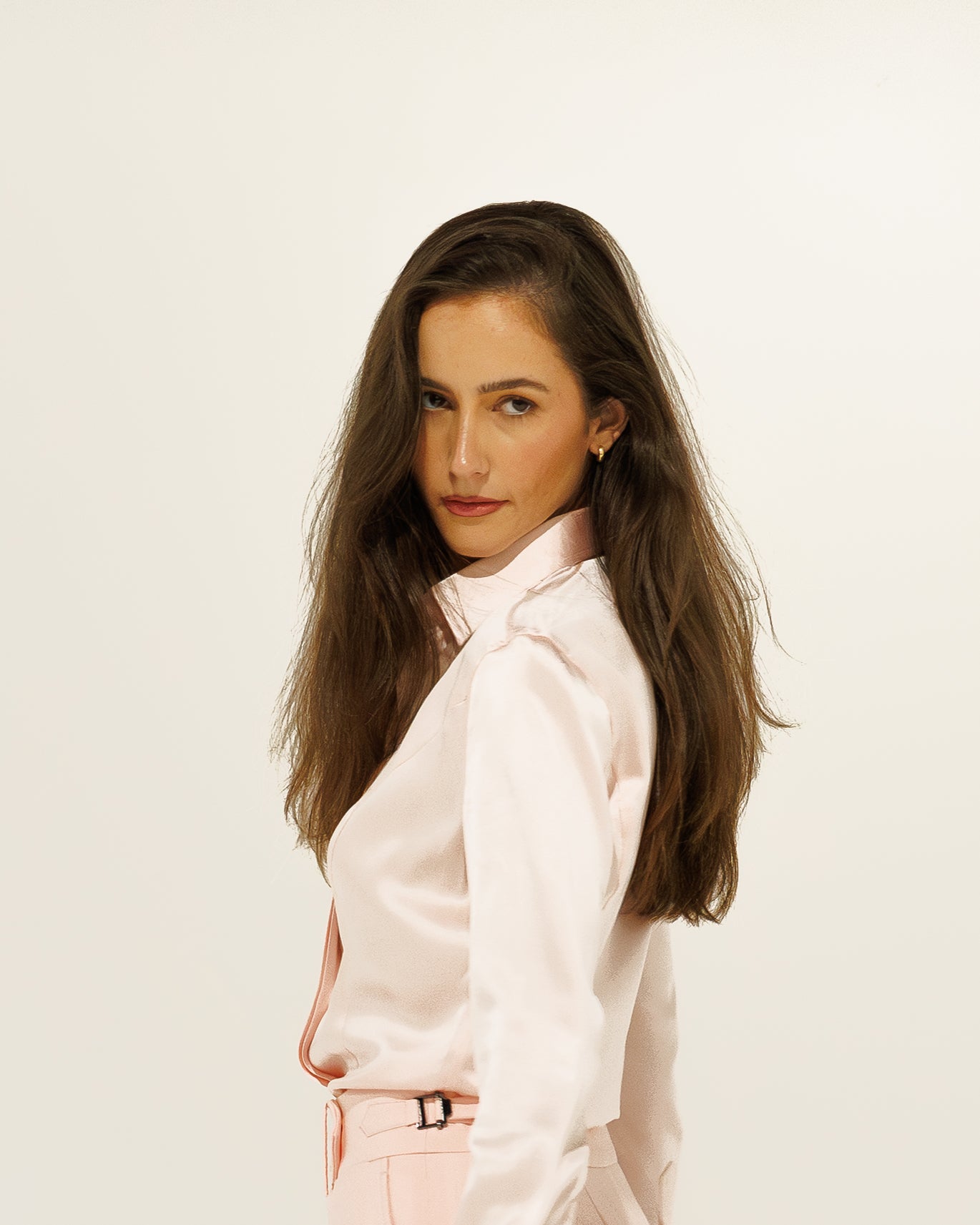 Woman wearing a light pink outfit against a plain background