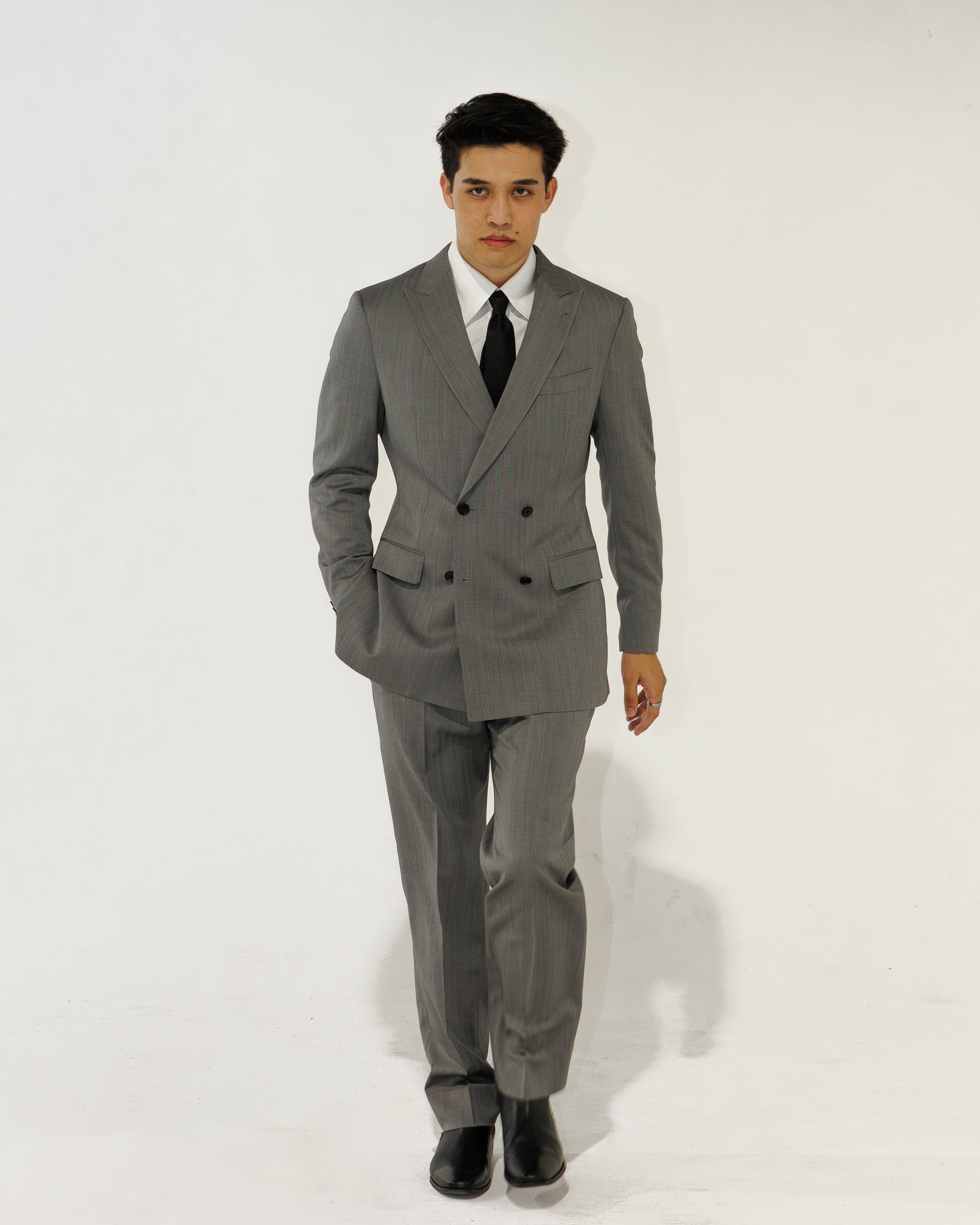 Man wearing a gray suit with a white shirt and black tie on a white background