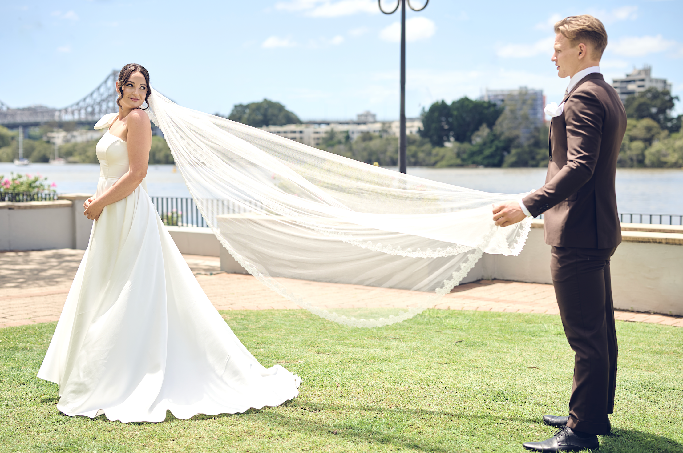 Man holding a woman's veil with a scenic background