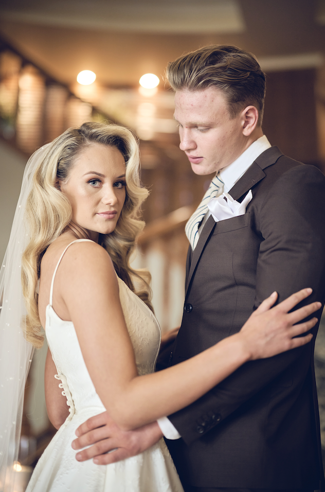 Man and woman embracing in a formal setting, possibly a wedding.